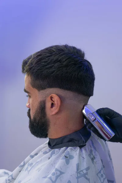 Berber, Amerikan çocuğuna saç kesiyor. Berber saç makasıyla saç kesenin arkasında durur.