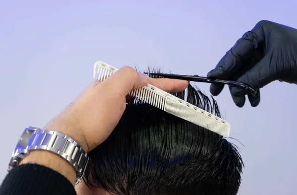 Berber kuaförde beyaz bir adamın saçını kesiyor. Berberin bir saç makası var. Ayrıntılı çekimleri olan yatay bir resim..