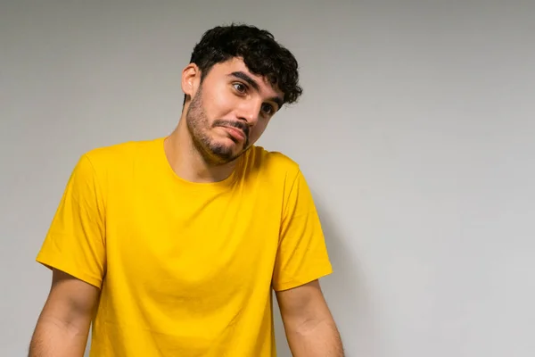 Beyaz, beyaz, kıvırcık saçlı, sarı tişörtlü, tenha beyaz arka planda şüpheli bir beyaz çocuk.