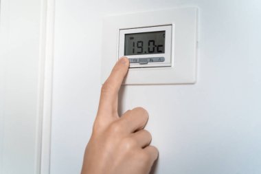 Kız ev ısıtma sorunu yüzünden üşüyor. Enerji krizi konsepti. Radyatör termostatı soğuk hava gösteriyor. Elektrik ve doğalgaz faturaları artıyor. Radyatörler kapanıyor. Isıtma problemi. Uzaklaşma