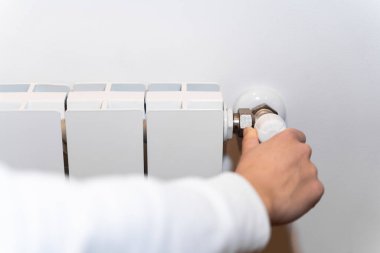 Kız ev ısıtma sorunu yüzünden üşüyor. Enerji krizi konsepti. Radyatör termostatı soğuk hava gösteriyor. Elektrik ve doğalgaz faturaları artıyor. Radyatörler kapanıyor. Isıtma problemi. Uzaklaşma