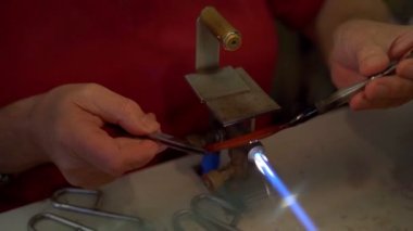 Murano glass blowing factory. Workers put iron rod in furnace to make glass malleable.Artist shaping hot glass into a figurine with gas flames. Artisan making glass vases and sculptures. Venice winter. Glass melting in a traditional oven of a glass