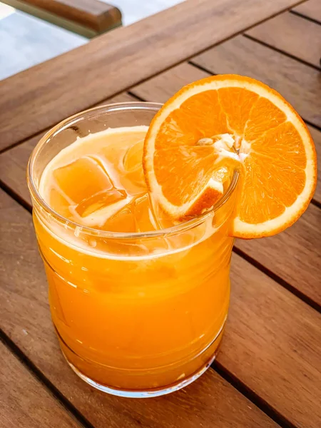 Tahta bir masada, bardakta portakal suyu.