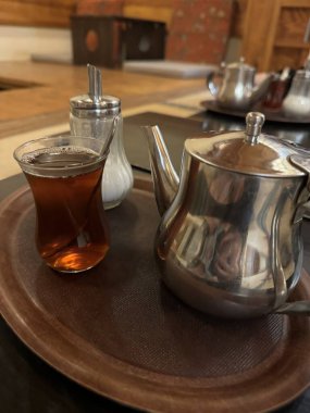 Çay fincanı ve çaydanlık ahşap masada.
