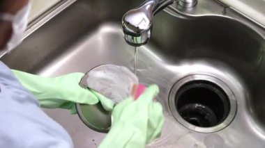 Kadınlar mutfak lavabosunu süngerle temizliyor.