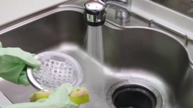 Kadınlar mutfak lavabosunu süngerle temizliyor.