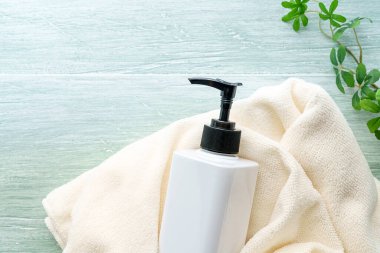 Sıvı sabun şişesi ve havlu ahşap masada.
