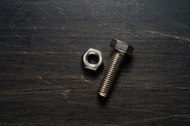 Çelik somunlar ve cıvatalar ahşap masaya yakın.