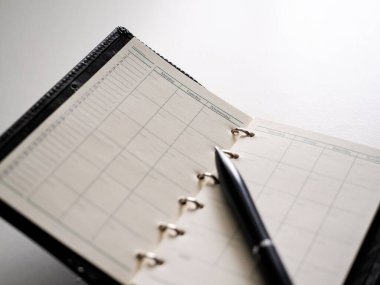 Beyaz arkaplanda halka bağlı planlayıcı ve kalem