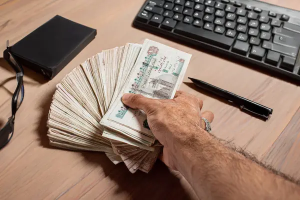 stock image Man arm Holding bundles of Egyptian money currency 100 pound on office White Background