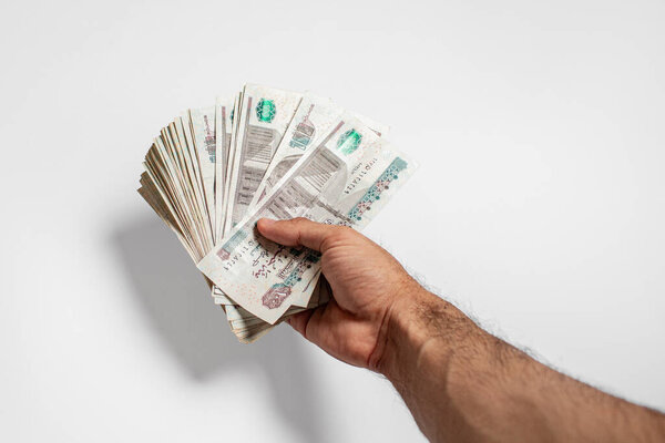 Hand Holding a Large Bundle of Egyptian Currency 100 Pound Notes White Background 