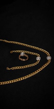 Altın zincirli bir kolye, uyumlu bir bilezik ve kare elmas aksanlı bir yüzükten oluşan lüks bir set. Karmaşık tasarım ve parlak elmaslar bu seti resmi olaylar için bir bildiri haline getiriyor..