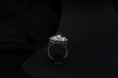 Parlak elmaslarla süslenmiş karmaşık çiçek desenli göz kamaştırıcı bir elmas yüzük. Siyah arka planda zarif bir şekilde duruyor. Düğün, nişan ya da son moda mücevher promosyonları için ideal.