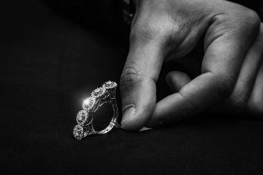 Zarif, siyah bir yüzeye yerleştirilmiş, eşsiz, bükülmüş bir bant içeren modern, beyaz, altın bir yüzük. Merkezi elmas görkemli bir şekilde parlıyor, zarafet ve çağdaş stilin mükemmel bir karışımını sunuyor, nişanlar ve moda için ideal bir ortam.