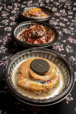 Üst üste üç gurme tarçınlı çöreğin karışımı. Kurabiye, çikolata parçacıkları ve seçici bir odak noktası olan siyah bir çiçeğin üzerine serpiştirilmiş çikolata parçacıkları.