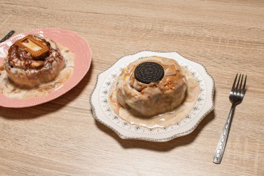 İki çeşit tarçınlı rulo, biri çikolatalı kurabiye, diğeri de karamelli bisküviyle servis edilen, ahşap bir arka planda servis edilen, paylaşılan tatlı.