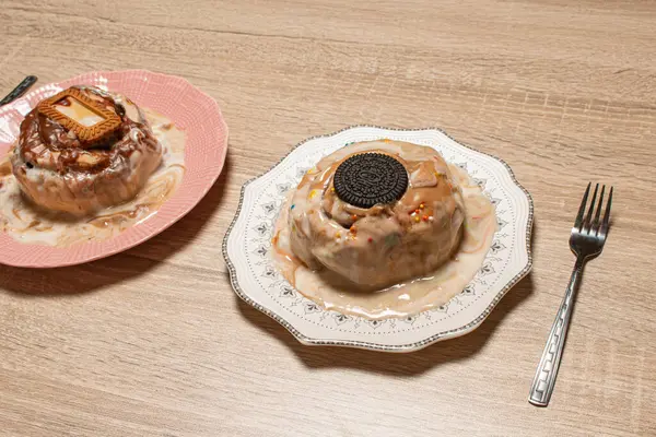 İki çeşit tarçınlı rulo, biri çikolatalı kurabiye, diğeri de karamelli bisküviyle servis edilen, ahşap bir arka planda servis edilen, paylaşılan tatlı.