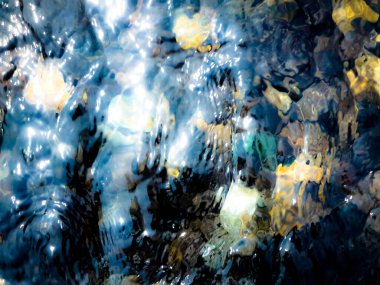 Güzel su dalgalanmaları ve renkli kayaların üzerinde yansımaları.