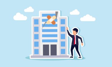 Kırık bir ofis binasının onarımını tıbbi bant kullanarak tamamlayan bir işadamı, zarar görmüş iş varlıklarının kurtarılmasının bir göstergesi.