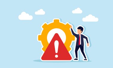 İşadamı, ünlem ya da dikkat levhası ile işaretlenmiş bir dişlinin yanında duruyor, üretim sistemi bakımı ya da iş sistemleri ihtiyacının bir göstergesi..