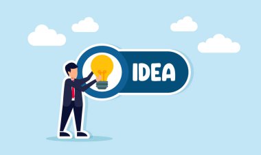 Fikir önerisi ve sosyalleşmenin tanıtımı olarak etiketlenmiş IDEA illüstrasyonu üzerine ampul yerleştiren iş adamı