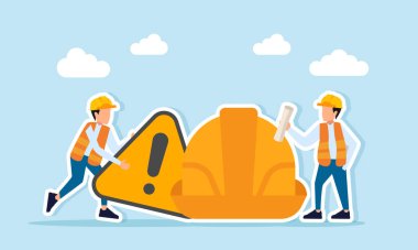 Mühendis uyarı jesti yaparken, diğeri güvenlik miğferi projesinin yanında işyeri güvenliği ilkelerinin bilinç ve uygulanmasına ilişkin belgeler tutuyor.