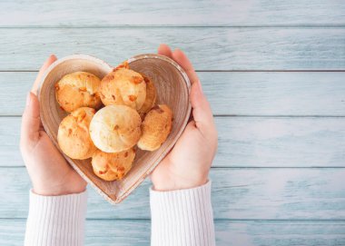 Peynirli ekmek (Brezilyalı Pao de Queijo mineiro) ve kahve, kalp şeklinde tabak, kadın eli, üst manzara düz