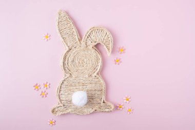 Handmade easter bunny made of strings with flowers on a light pink background