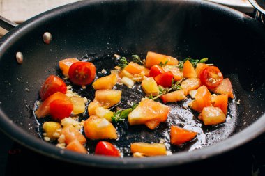 Fried tomatoes and garlic on a pan, sauce for pasta, italian meal preparing, detailed focused view