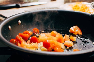 Fried tomatoes and garlic on a pan, sauce for pasta, italian meal preparing, detailed focused view