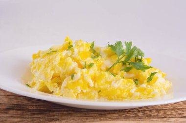 Scrambled eggs on plate, wooden table, front view