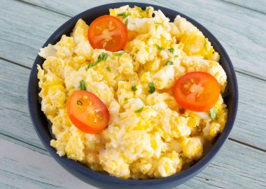 Scrambled eggs on bowl, wooden table