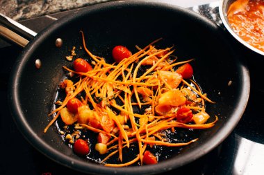 Kızarmış domates ve rendelenmiş havuç, makarna sosu, İtalyan yemeği hazırlama, ayrıntılı odaklı görüş.