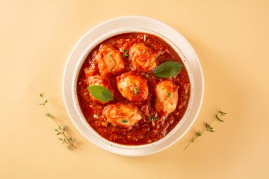 Kırmızı sos ve fesleğenli lezzetli Gnocchi bej arkaplanda beyaz desenli el yapımı seramik kasede servis edilir.