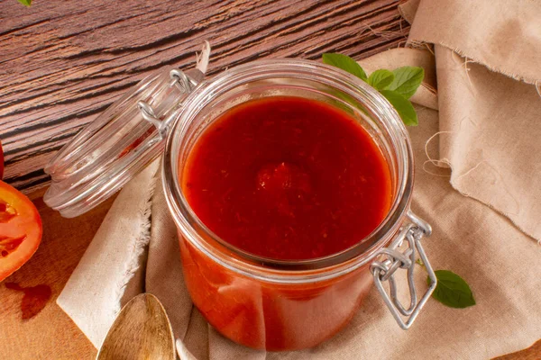 Świeży Sos Pomidorowy Szklanym Słoiku Drewnianym Stole Czerwone Tło Widoku — Zdjęcie stockowe