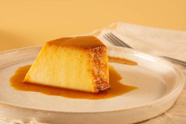 Krem Karamel Yoğunlaştırılmış Süt Pudim dilimi bej arka planda