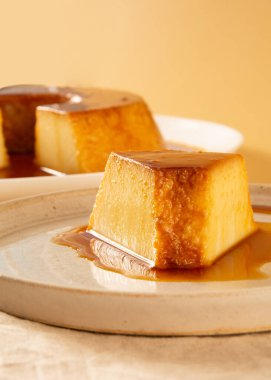 Krem Karamel Yoğunlaştırılmış Süt Pudim dilimi bej arka planda