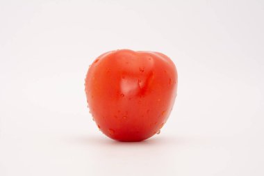 Önünde temiz beyaz arkaplanda izole edilmiş kırmızı bir domates.