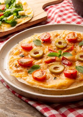 Önünde el yapımı seramik tabakta domatesli ve peynirli pizza.