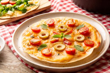 Önünde el yapımı seramik tabakta domatesli ve peynirli pizza.