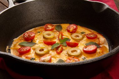 Peynirli pizza tavası, kiraz domatesli ve zeytinli, demir tavada, kırpılmış ön manzara.