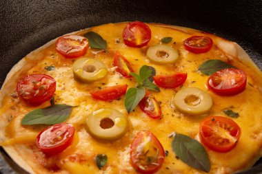 Peynirli pizza tavası, kiraz domatesli ve zeytinli, demir tavada, kırpılmış ön manzara.