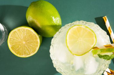 Buzlu Caipirinha bardağı ve limonlu buzlu kokteyl ve limonlu yeşil arka plan.