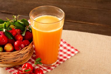 Bambu bir yerde, cam bir fincanda taze acerola suyu dilimlenmiş portakallar ve acerola öngörüsüyle birlikte.