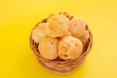 Brezilya peyniri, ahşap bir sepetin içinde izole edilmiş, sarı arka planda.