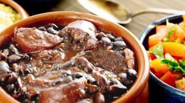 Brezilyalı Feijoada Domuz pastırmalı siyah fasulye güveci ve domuz sosisi kasesi.