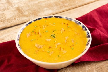 Creme de cenoura com frango desfiado, ervas frescas e pimenta calabresa vista isometrica frontal