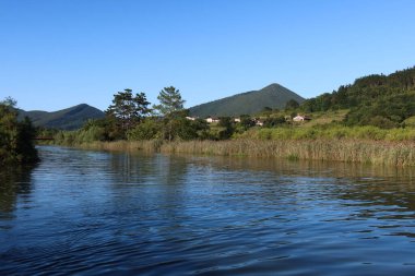 Mundakako İtsasadarra Nehri, İspanya 'nın Bask Bölgesi' ndeki Urdaibai Reserve 'den geçer. Yeşil tepeler tarafından çerçevelenmiş ve önplanda uzun otlar, doğal çevrenin güzelliğini yansıtıyor.