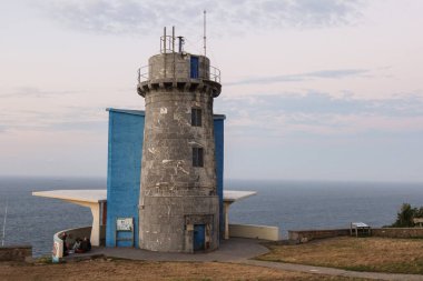 The Matxitxako Lighthouse rises against the backdrop of the deep blue ocean. Above, the sky is painted with soft pink dusk, creating a perfect contrast to the rugged coastline of the Basque Country clipart