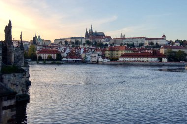 Günbatımında Prag Kalesi ve St. Vitus Katedrali 'nin Panoramik Manzarası, Vltava Nehri' nin karşısından Küçük Kasabanın İkonik Kırmızı Çatıları ile görülüyor